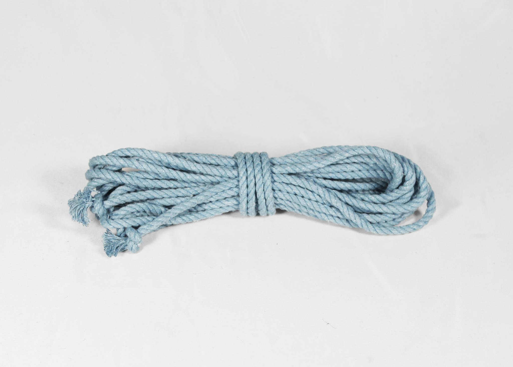 A coiled light blue cotton rope with frayed ends, photographed on a plain white background.