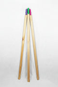 Three poles standing upright in a V-shape arrangement, with colourful plastic tips in green, purple, and pink visible at the top, set against a plain white background.